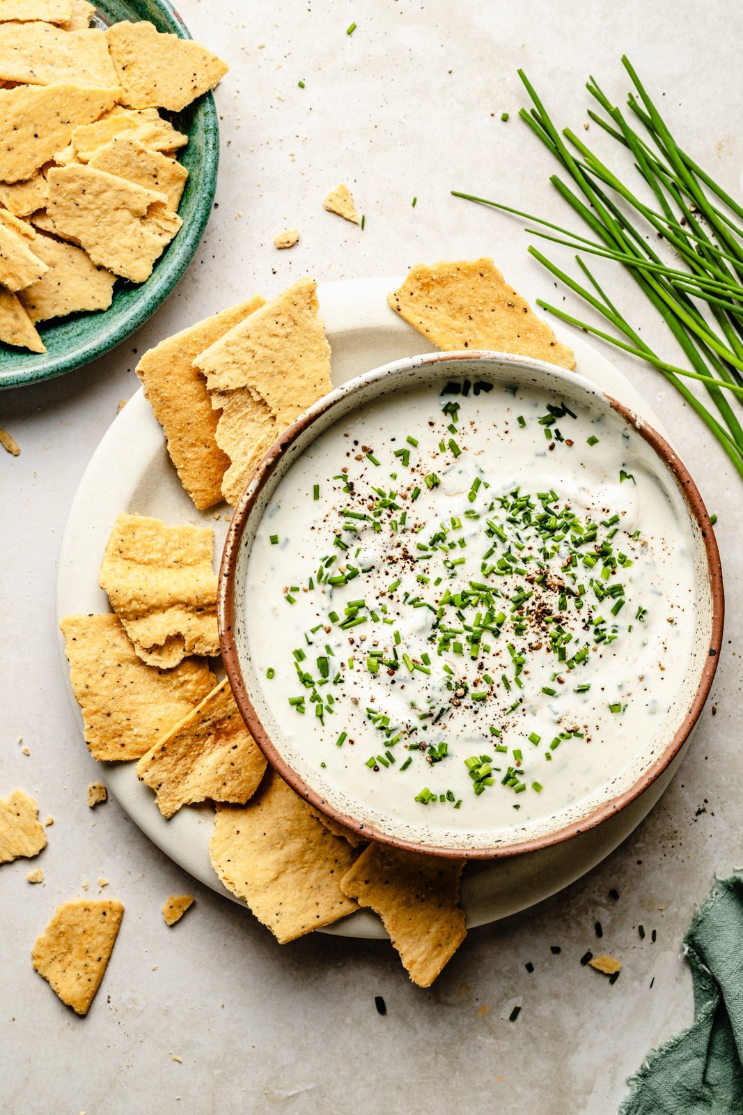 healthy sour cream and onion dip in a bowl next to a plate of crackers