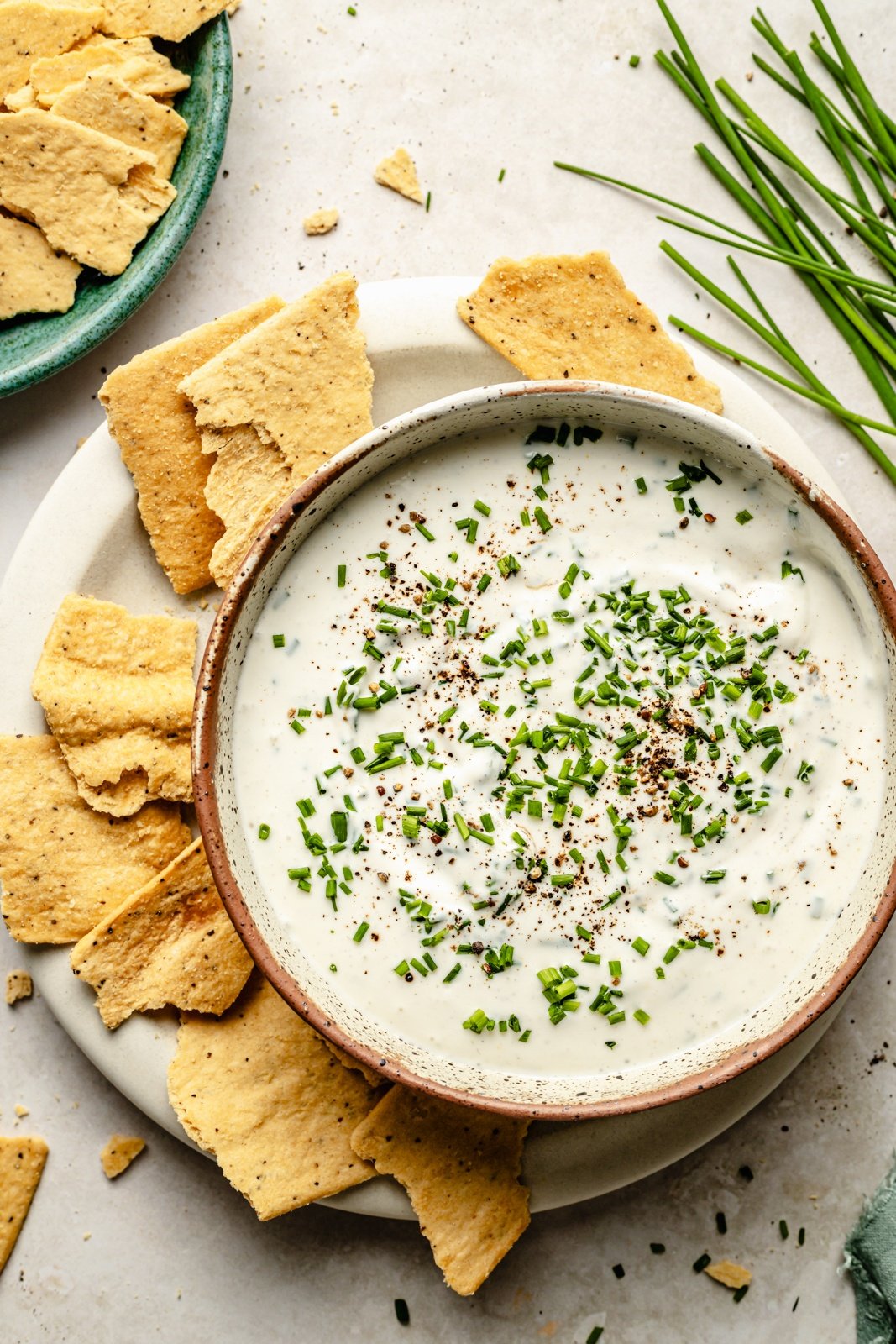 high protein sour cream and onion dip in a bowl next to a plate of crackers