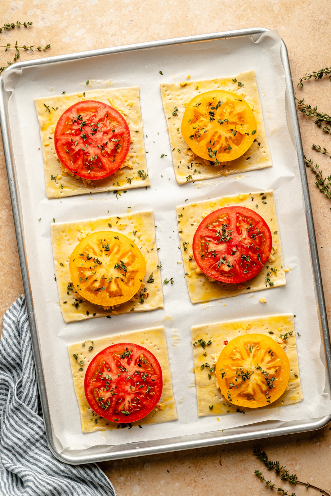 unbaked tomato tarts on a baking sheet