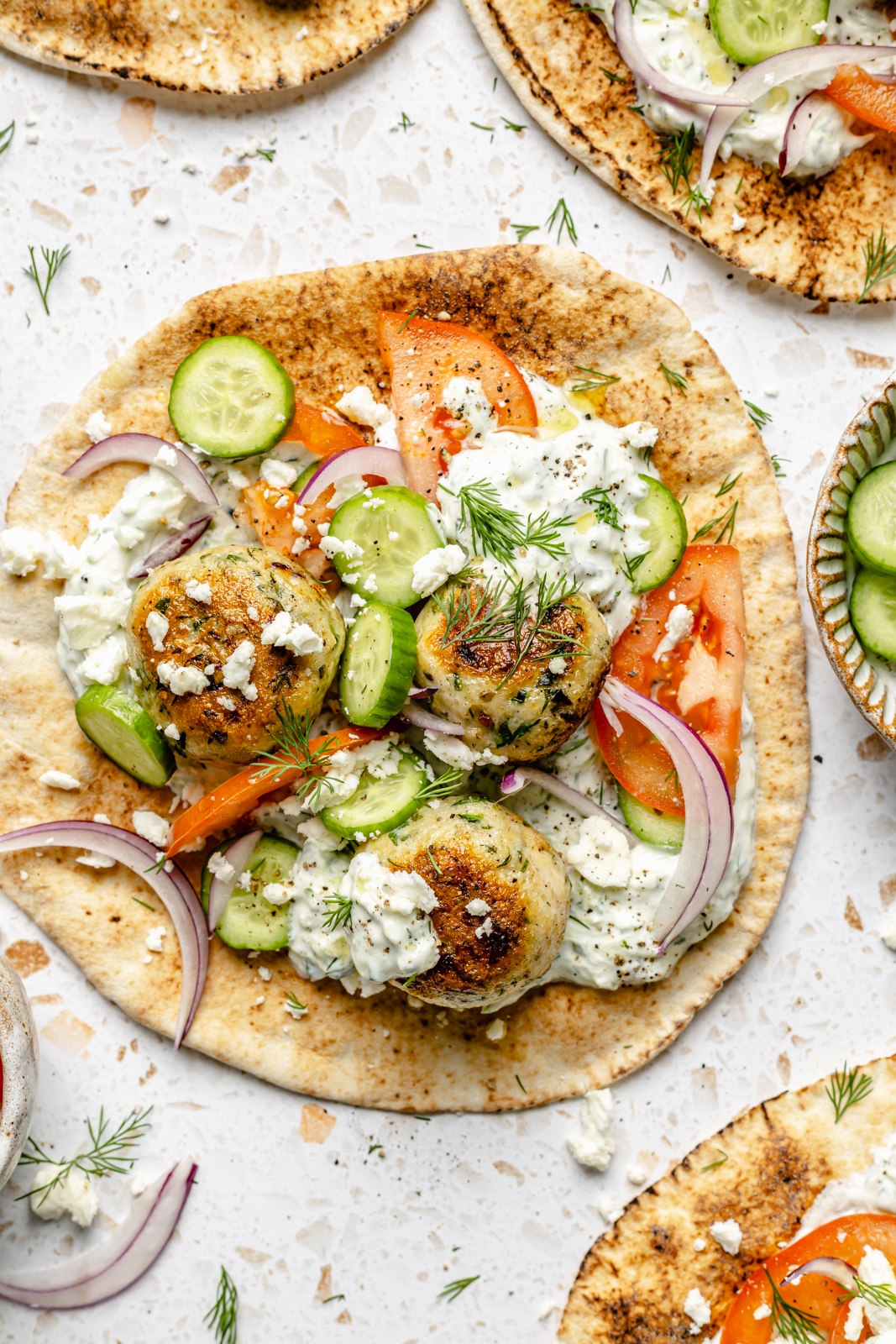 herby chicken meatball pitas topped with tzatziki and vegetables