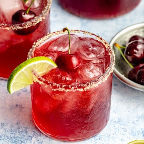 cherry lime cocktail garnished with a lime wedge and a cherry