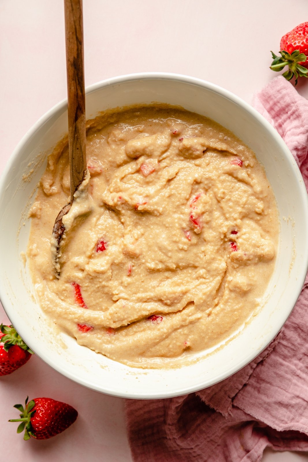 healthy strawberry bread batter in a bowl with a wooden spoon