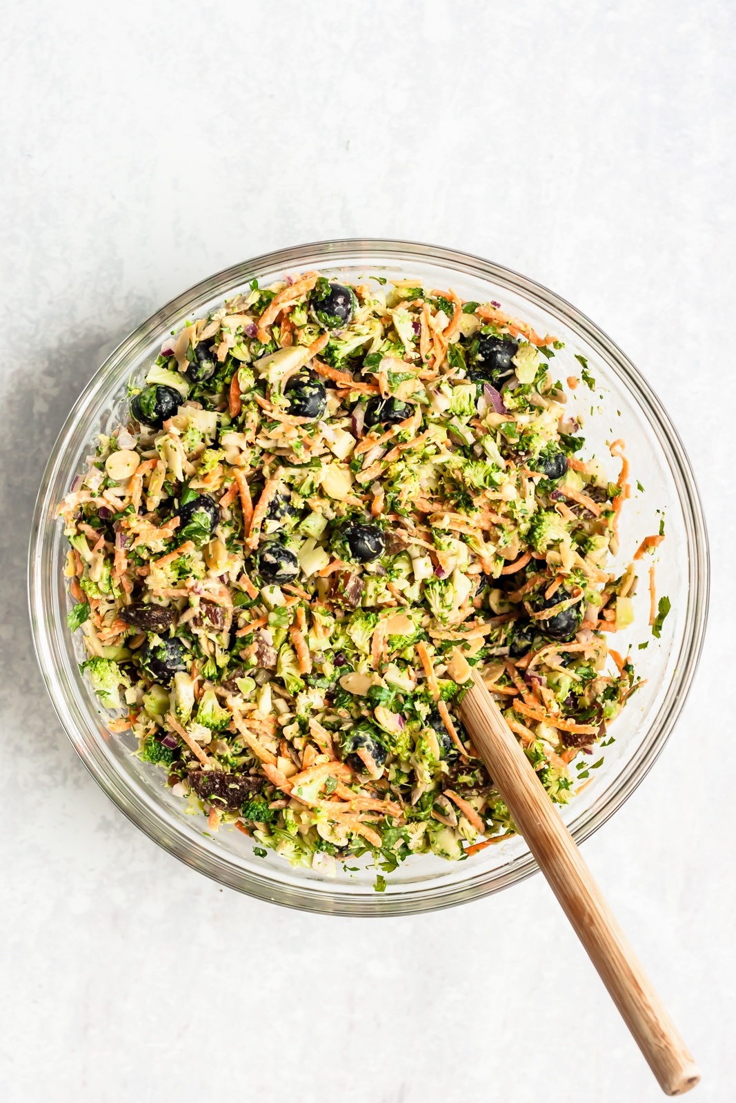 easy and light broccoli salad in a glass bowl with a wooden spoon