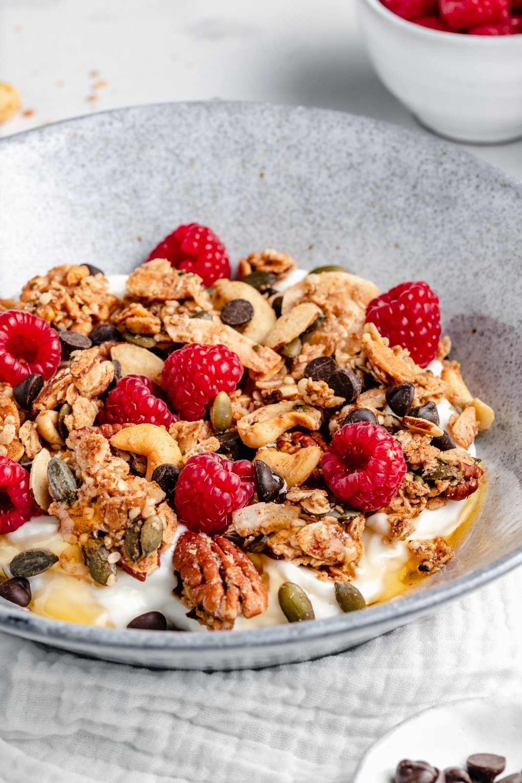 nut and seed granola in a bowl with yogurt and raspberries