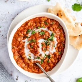 vegan tomato lentil soup in a bowl with naan