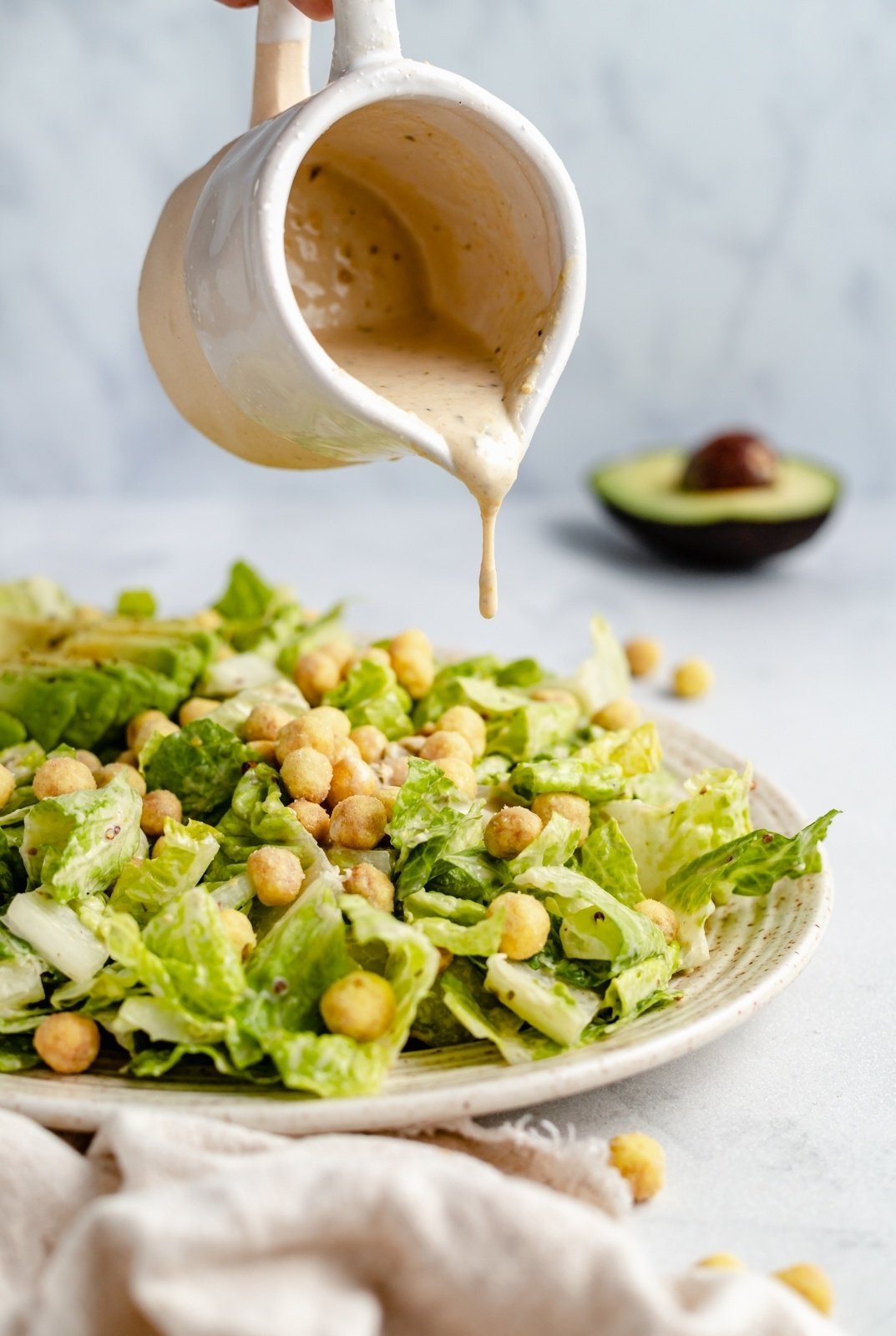 pouring dressing on a vegan caesar salad