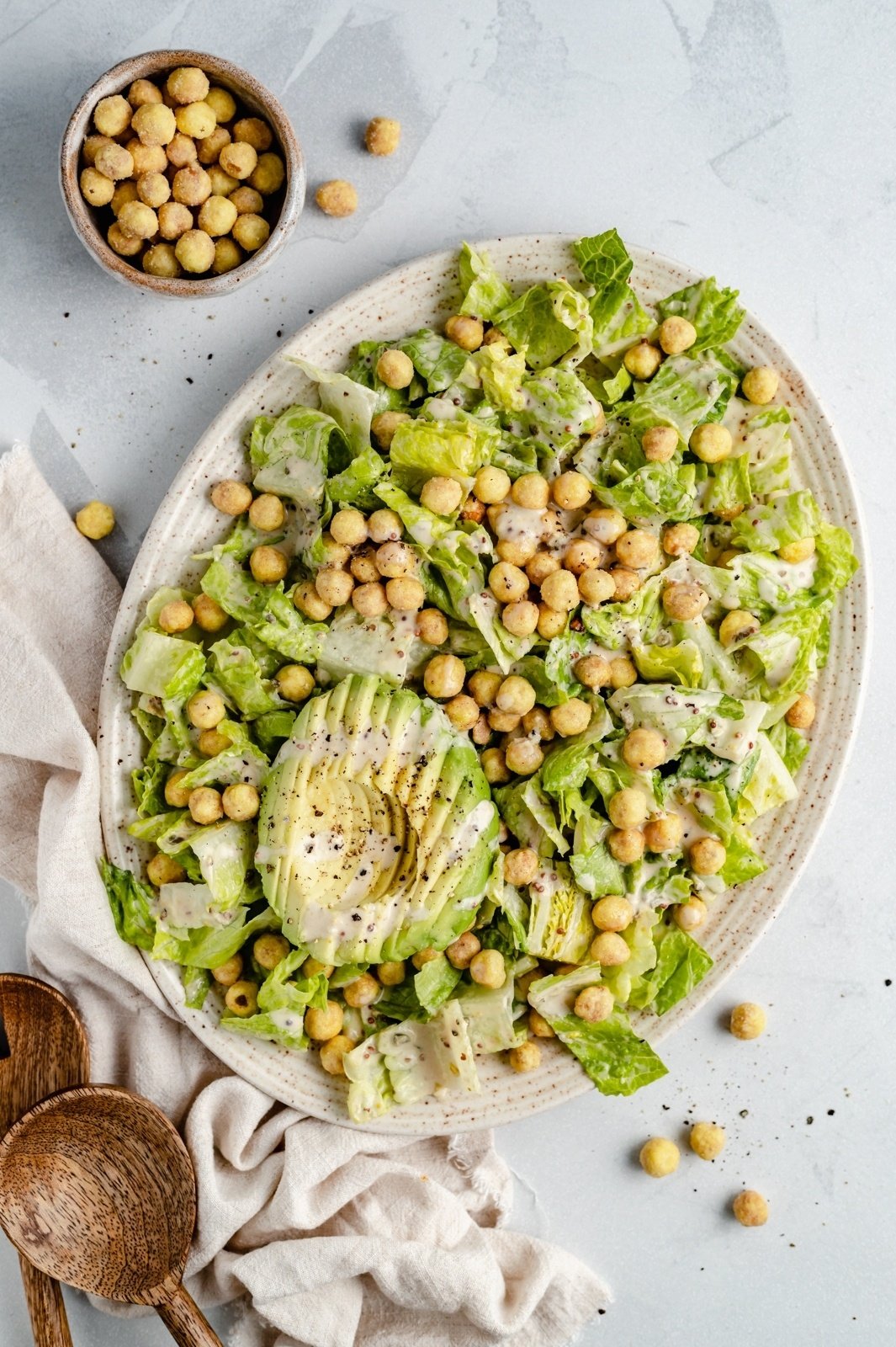 vegan caesar salad with avocado and chickpeas on a platter