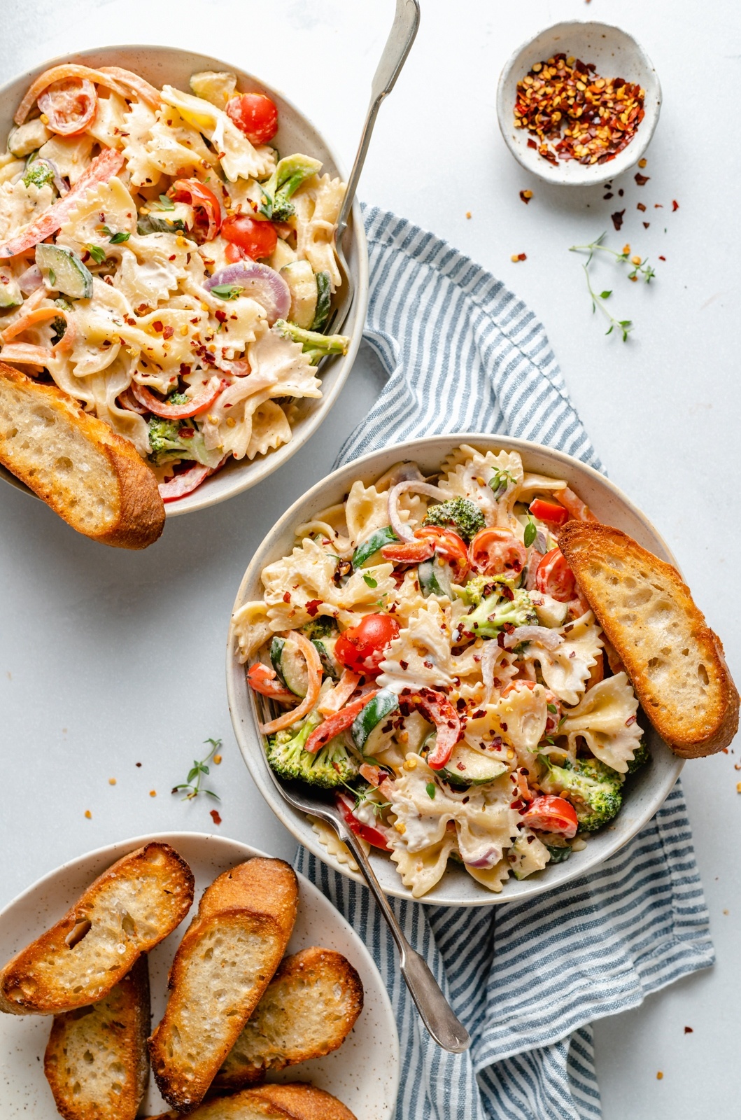 the best vegan pasta primavera in two bowls with garlic bread