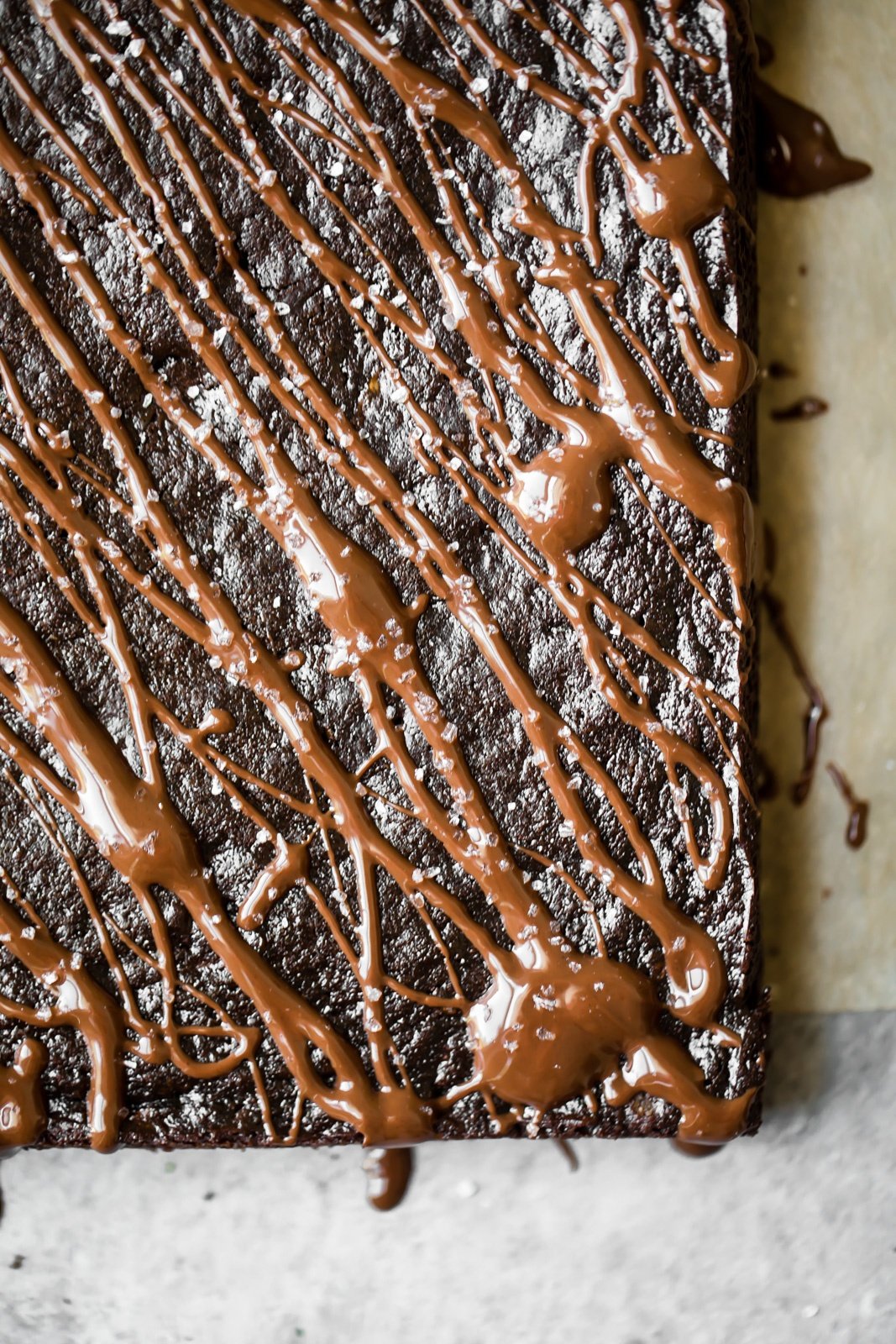 gluten free zucchini brownies drizzled with chocolate on parchment paper